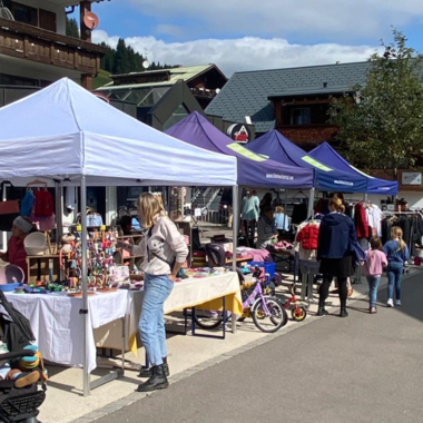 A busy market with several stalls and visitors. The atmosphere is friendly and there is a variety of products to see.