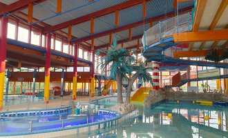 Ein modernes Freizeitbad mit einem großen Wasserbecken und verschiedenen Rutschen. Palmen sorgen für ein tropisches Ambiente. | © Wonnemar Sonthofen | interSPA Gruppe