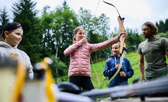 Ein Logo der Wildnisschule Kleinwalsertal. Es zeigt ein Feuer über Holzscheiten und symbolisiert Abenteuer in der Natur. | © Kleinwalsertal Tourismus eGen - Fotograf: Oliver Farys