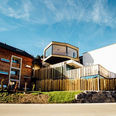 A modern building with wooden cladding and large windows. It is situated in a quiet environment and has an appealing architecture.