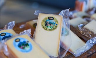 Eine Auswahl von verpacktem Käse auf einem Tisch. Der Käse hat verschiedene Etiketten und Verpackungen.