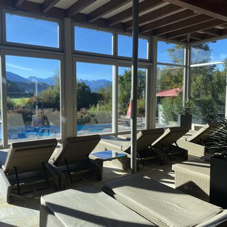 Ein heller Ruheraum mit Liegen und großen Fenstern. Im Hintergrund sind Berge und ein Pool sichtbar. | © Wonnemar Sonthofen | interSPA Gruppe