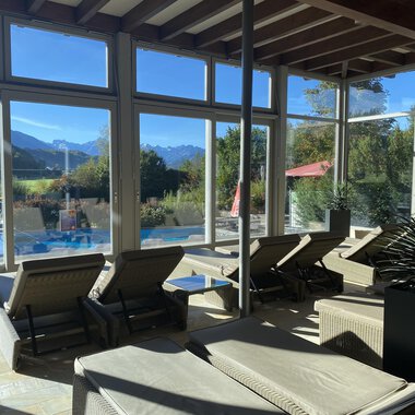 Ein heller Ruheraum mit Liegen und großen Fenstern. Im Hintergrund sind Berge und ein Pool sichtbar. | © Wonnemar Sonthofen | interSPA Gruppe