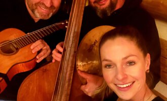 Three musicians pose together with their instruments in a warm, rustic room. They are smiling and seem to be having fun. | © Kulturcafe Kleinwalsertal | Matthias Zobel