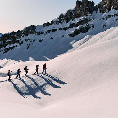 Eine Gruppe von Wanderern geht über eine schneebedeckte Landschaft. Im Hintergrund sind majestätische Berge zu sehen. | © Kleinwalsertal Tourismus eGen | Oliver Farys