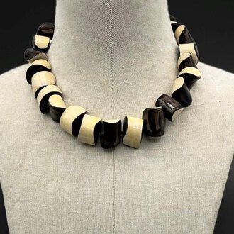 An elegant necklace made of alternating black and white pearls. It has a curved shape and adds a stylish look. | © Gerti Maitz