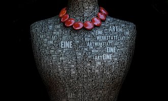 An artistic representation of a mannequin covered in words about art. It wears a striking necklace made of red beads. | © Gerti Maitz