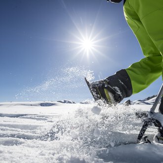 Ein sonniger Tag im Schnee mit einem Menschen, der mit einem Skistöck im Schnee arbeitet. Im Hintergrund ist eine weitere Person zu sehen. | © Kleinwalsertal Tourismus | Dominik Berchtold
