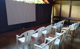 A room with white plastic chairs and a screen. The environment is quiet and well-suited for presentations or movies. | © Kulturcafe Kleinwalsertal | Gerhard Bauer