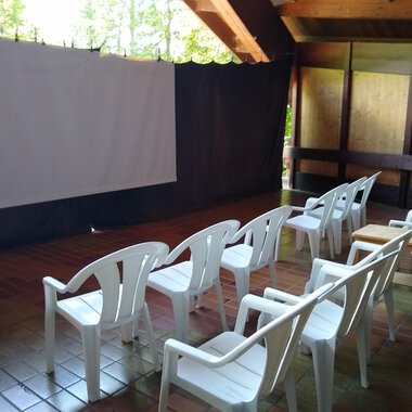 A room with white plastic chairs and a screen. The environment is quiet and well-suited for presentations or movies. | © Kulturcafe Kleinwalsertal | Gerhard Bauer