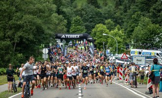 A large running event with many participants starting on a street. In the background, trees and a starting line are visible. | © Kleinwalsertal Tourismus - Dominik Berchtold