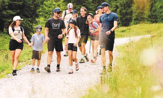 Eine Gruppe von Menschen wandert auf einem schmalen Weg durch die Natur. Umgeben von grünen Bäumen genießen sie die frische Luft und die Gemeinschaft. | © Kleinwalsertal Tourismus | Oliver Farys