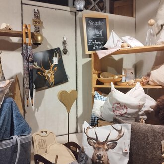 © Abler Mittelberg | N. Lughammer Ein gemütlicher Raum mit verschiedenen Kissen und Dekorationsartikeln. Auf einem Regal befinden sich Artikel mit Tiermotiven und Holzaccessoires. | © Abler Mittelberg | N. Lughammer