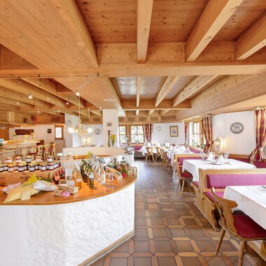 Ein gemütliches Restaurant mit Holzbalkendecke und freundlicher Atmosphäre. Tische sind gedeckt und ein Buffet mit verschiedenen Leckereien ist sichtbar. | © Alpengasthof Hörnlepass | Monschau Michael