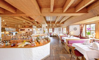 Ein gemütliches Restaurant mit Holzbalkendecke und freundlicher Atmosphäre. Tische sind gedeckt und ein Buffet mit verschiedenen Leckereien ist sichtbar. | © Alpengasthof Hörnlepass | Monschau Michael