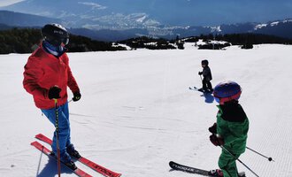 Eine Gruppe von Skifahrern auf einer schneebedeckten Piste. Im Hintergrund sind beeindruckende Berge zu sehen. | © Austrian Ski- & Service Ranch | Trixi Leitner