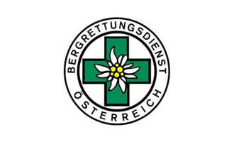 A logo of the Austrian Mountain Rescue Service. It features a green cross with an alpine flower in the center. | © Bergrettung Mittelberg Hirschegg Logo