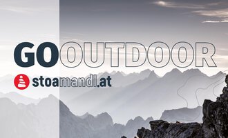 Eine beeindruckende Berglandschaft im Hintergrund mit sanften Hügeln und grauem Himmel. Im Vordergrund steht der Schriftzug "GO OUTDOOR" sowie das Logo von stoamandl.at. | © stoamandl