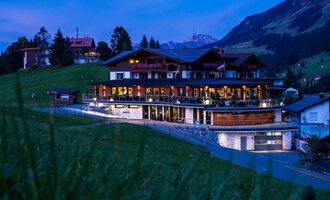 A modern building in the mountains, illuminated at twilight. Surrounded by green meadows and dense forests. | © Hotel Birkenhöhe | Fotos GA Service Salzburg