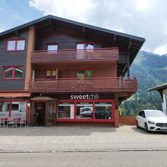 A modern building with two floors in the mountains. The ground floor houses the restaurant "sweetchill" with large windows. | © Kleinwalsertal Tourismus | N. Lughammer