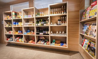 Ein gut sortierter Verkaufsregal mit Lebensmitteln, Getränken und Zeitschriften. Die Regale sind aus Holz und bieten eine Vielzahl von Produkten an. | © Campingplatz Vorderboden GmbH | Marion Schwendiger