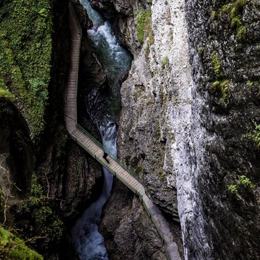A picturesque gorge with steep cliffs and a flowing brook. Lush greenery surrounds the area, creating a tranquil atmosphere. | © Breitachklamm | Dominik Berchtold