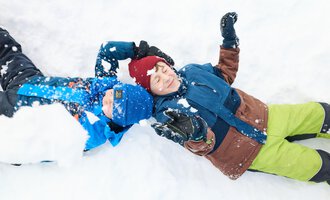Ein Schlitten steht im Schnee, umgeben von schneebedeckten Bergen. Die Sonne strahlt im Hintergrund und erzeugt eine malerische Winterlandschaft. | © Kleinwalsertal Tourismus | Oliver Farys