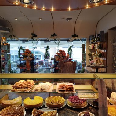 A cozy bakery with a selection of sweet and savory baked goods. In the background, you can see tables and chairs for guests. | © Kleinwalsertal Tourismus | N. Lughammer