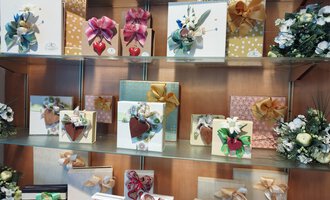 Eine Vitrine mit schön verpackten Geschenken in verschiedenen Farben und mit kunstvollen Schleifen. Die Geschenke sind unterschiedlich groß und einige haben Herz- oder Blumenmotive. | © Kleinwalsertal Tourismus | N. Lughammer