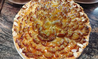 Ein köstlicher Obstkuchen mit einer kunstvollen Anordnung von Früchten und Mandeln. Die goldene, glänzende Oberfläche macht ihn besonders appetitlich. | © Kleinwalsertal Tourismus | N. Lughammer