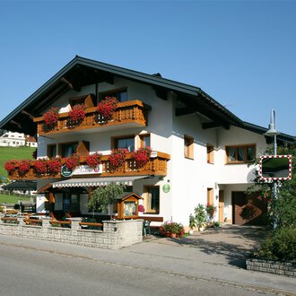 © Cafe Jochum | Bernadette Reinmuth Ein malerisches Gebäude im alpinen Stil mit blühenden Balkonen. Es liegt in einer ruhigen, grünen Umgebung. | © Cafe Jochum | Bernadette Reinmuth