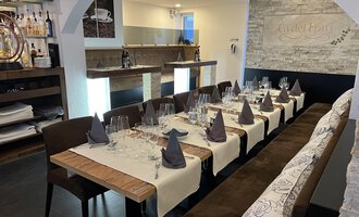 Ein elegant eingedeckter Tisch in einem Restaurant mit dunklen Stühlen und dekorierten Servietten. Der Raum hat eine moderne, einladende Atmosphäre.