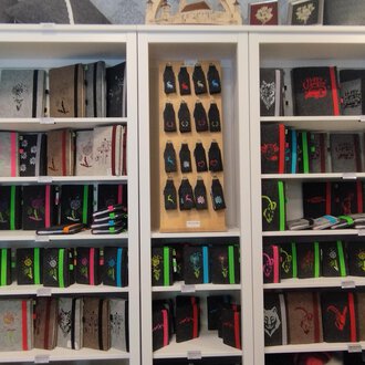 © Chrömle Schönes aus Filz | N. Lughammer A bookshelf with many notebooks in various colors and designs. Below are colored pens and other stationery. | © Chrömle Schönes aus Filz | N. Lughammer