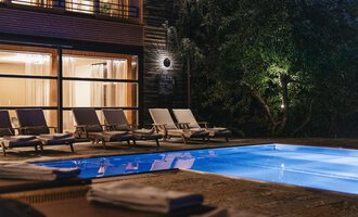 An elegant pool area with loungers and soft lighting. The pool reflects the light of the surroundings and creates a relaxed atmosphere. | © Naturhotel Chesa Valisa
