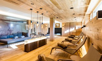 Ein eleganter Wellnessbereich mit Holzverkleidung und modernen Liegestühlen. Der Raum ist hell und bietet eine entspannende Atmosphäre. | © Genuss- & Aktivhotel Sonnenburg | Werner Krug