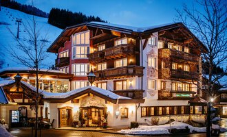 Ein gemütliches Hotel in den Bergen bei Nacht. Die Fassade ist beleuchtet und umgeben von schneebedeckten Bäumen. | © Hotel Alpenstüble KG