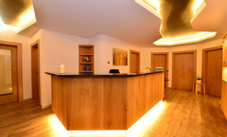 Ein modernes Empfangsbereich mit einer Holztheke und sanfter Beleuchtung. Die Wände sind neutral gehalten, was eine einladende Atmosphäre schafft. | © Hotel Alpenstüble KG