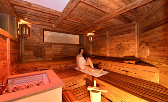 A cozy sauna with wooden walls and benches. A relaxed person is sitting in the room and enjoying the warmth. | © Hotel Alpenstüble KG