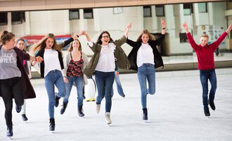 A group of cheerful teenagers is skating on an ice rink. They are laughing and having fun while ice skating. | © Sportstätten Oberstdorf | Veronika Lindlbauer