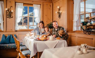 Eine Familie genießt ein Frühstück in einem gemütlichen Holzhaus. Auf dem Tisch sind verschiedene Frühstücksgerichte und eine freundliche Atmosphäre. | © Hotel Alpenstüble KG
