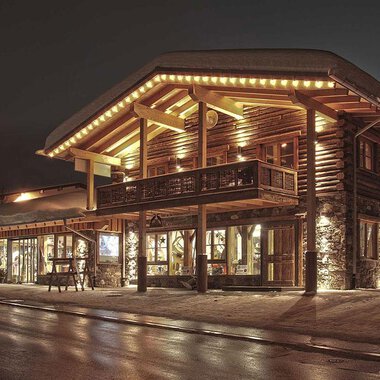 Ein charmantes Holzgebäude mit warmem Licht in der Nacht. Die Fassade ist gemütlich und einladend. | © Fun-Alp