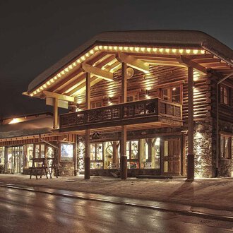 Ein charmantes Holzgebäude mit warmem Licht in der Nacht. Die Fassade ist gemütlich und einladend. | © Fun-Alp