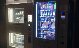 A vending machine in the dark with a variety of snacks and drinks. The machine glows and offers a colorful selection for customers. | © Gerd am Herd | Gerd Hammerer