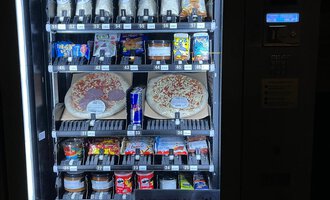 A snack vending machine with various drinks and foods. Among them are pizzas, candies, and energy drinks. | © Gerd am Herd | Gerd Hammerer
