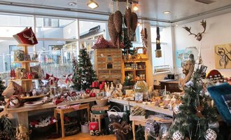 An inviting gift shop with festive decorations. Christmas trees and lovingly designed products can be seen everywhere. | © HUIMWEA Alpendekor