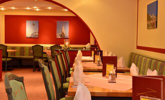 Ein elegantes Restaurant mit geschmackvoll dekorierten Tischen. Die Wände sind in warmen Farben gehalten und mit Bildern geschmückt. | © IFA Breitach Apartements