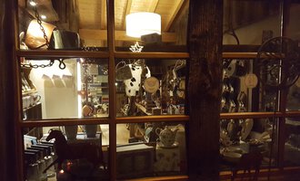 An insight into a cozy retail space with many decorative items and dishes. Stylish furniture and light sources are visible in the background.