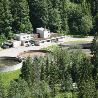 Eine moderne Kläranlage umgeben von dichtem Wald. Es gibt mehrere große runde Becken und ein Verwaltungsgebäude. | © Gemeinde Mittelberg