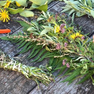 A table with fresh herbs and colorful flowers. Someone is tying a herb wreath with scissors beside it. | © Kleinwalsertal Tourismus | Lydia Fritz-Ilg