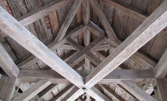 A wooden ceiling with visible beams and a textured design. The natural patina of the wood gives the space a rustic charm. | © Stefan Heim